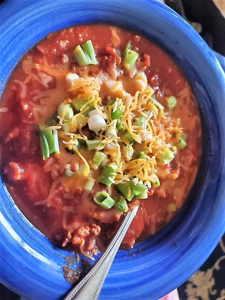Bowl of chili with cheese and onions